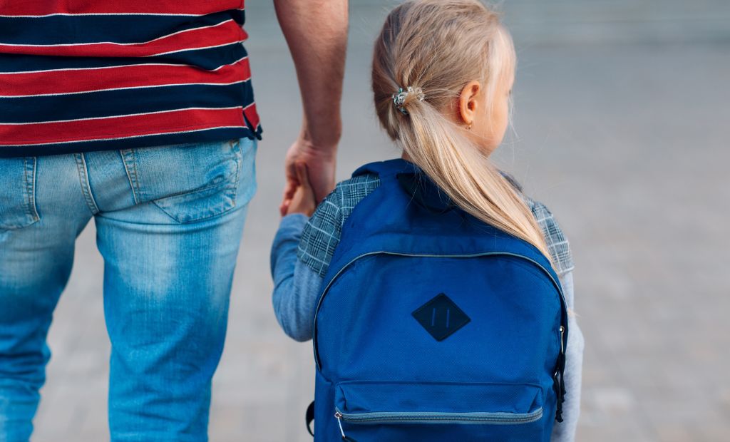 Genitore accompagna la figlia con zaino verso la scuola paritaria